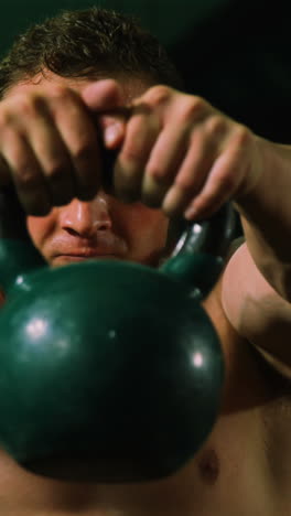 muscular man lifting kettle bell