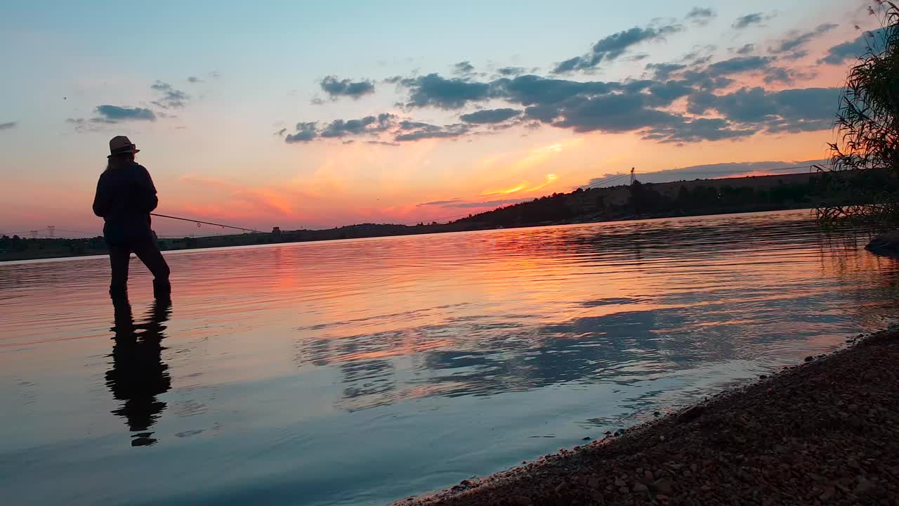 una niña pescando lubina después del atardecer en un hermoso lago tranquilo