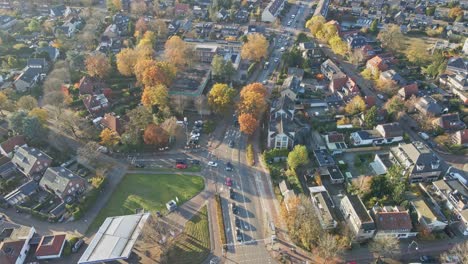 aerial of cars driving over a busy main road in a beautiful small town on a sunny autumn day