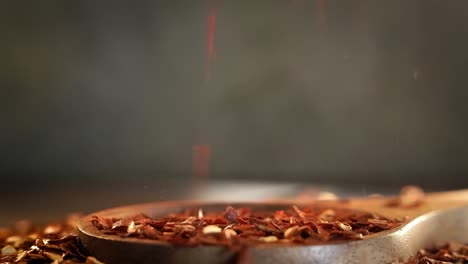 flakes of red hot chili pepper in wooden spoon closeup on a kitchen table.