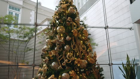 elegant christmas tree display in a shopping mall with glowing golden decorations - tilt down shot