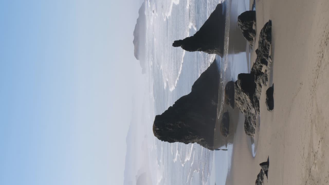 Un turista ammira le formazioni rocciose della costa dell'Oregon camminando tra i loro riflessi