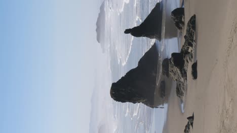 A-tourist-admires-the-rock-formations-of-the-Oregon-coast-walking-in-their-reflections