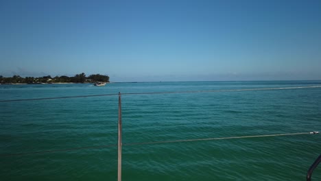 A-minimalism-shoot-taken-from-a-catamaran-of-the-coast-line,-with-another-tiny-boat-sailingin-the-background