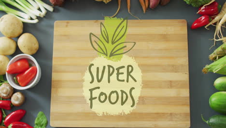 super foods text animation over wooden cutting board surrounded by fresh vegetables