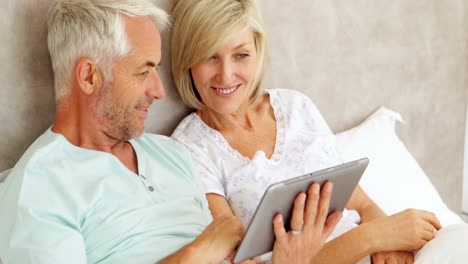 couple chatting and using tablet in bed
