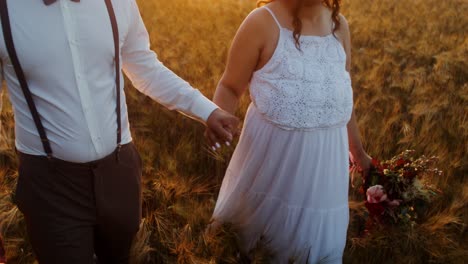couple walking in a wheat field at sunset