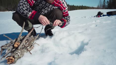 Portrait-Of-A-Man-In-Frozen-Ground-With-Dried-Tree-Branches-Making-Campfire