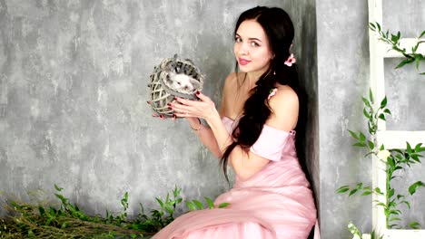 happy young lady having fun with white domestic rabbit in photo studio, photo session backstage