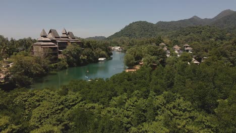 vista aérea de drones de un río tropical con un gran resort de lujo y montañas con paddle boarders remando río abajo en la isla de koh chang, tailandia