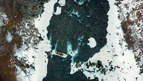aerial along a frozen river and across a small bridge in norway