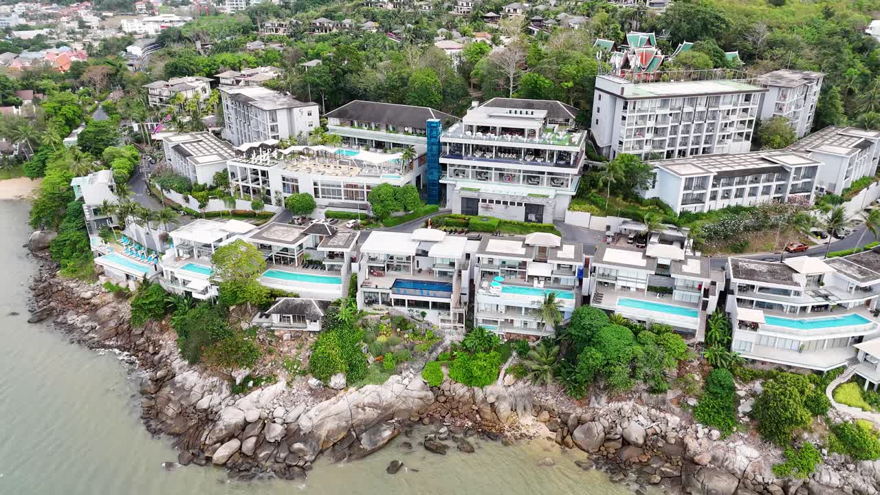 태국 푸켓의 바위가 있는 해안선에 있는 럭셔리 빌라를 보여주는 공중 영상, 울창한 초록색과 바다 전망