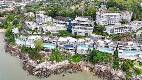 imágenes aéreas que muestran villas de lujo en una costa rocosa en phuket, tailandia, con exuberante vegetación y vistas al océano