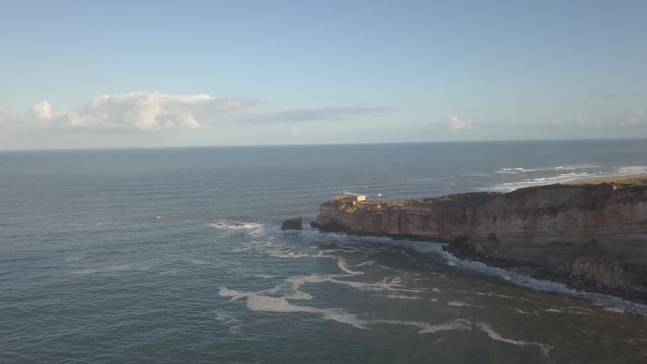 An iconic place on the Atlantic coast, the Mecca of big-wave surfing. View of Nazare's lighthouse in Zon North Canyon, place with the biggest waves in Europe, Nazare, Portugal