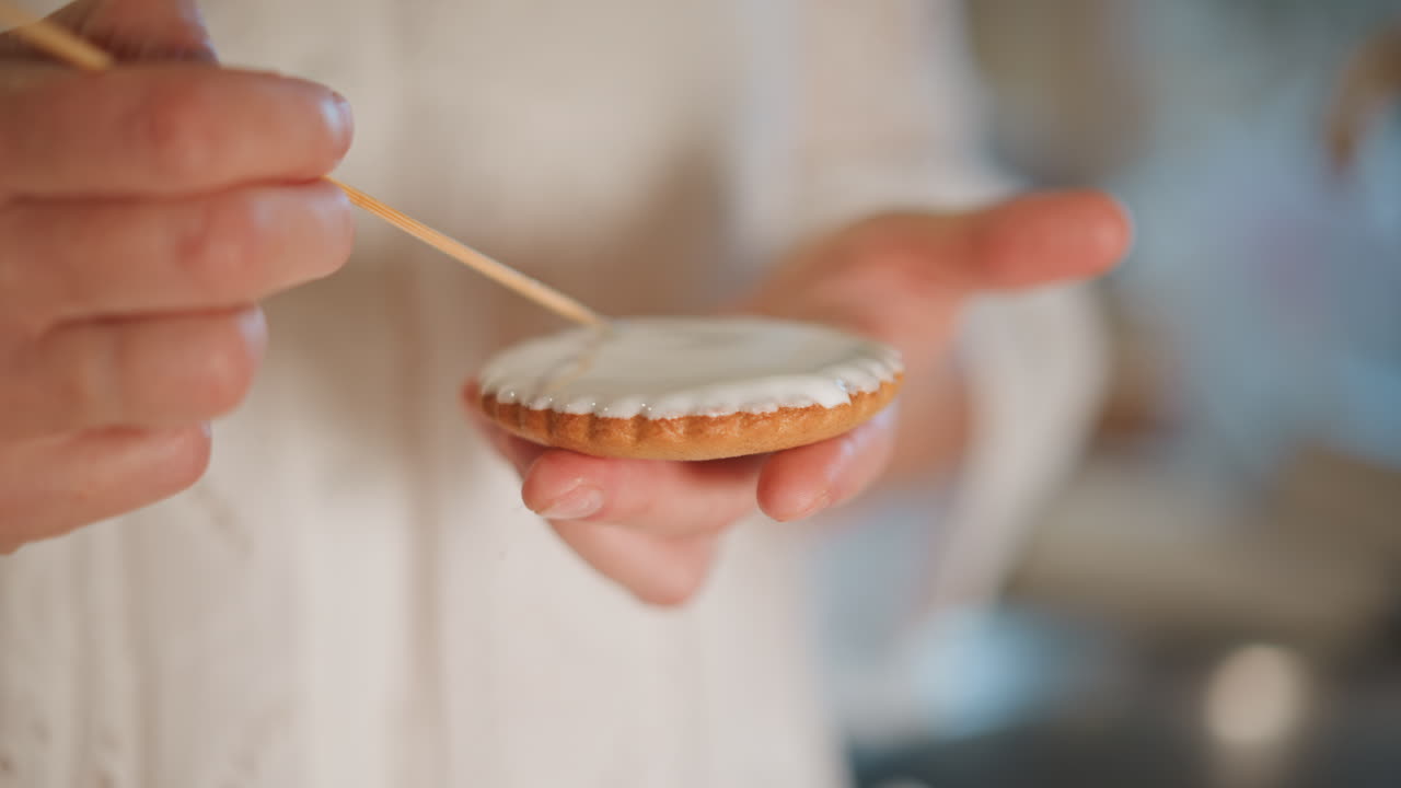 Closeup hand decorating pumpkin pie tart with icing using toothpick tool, delicate artisan technique in bright kitchen, smooth glaze and fingertip control, focus on texture and pattern, quiet precise