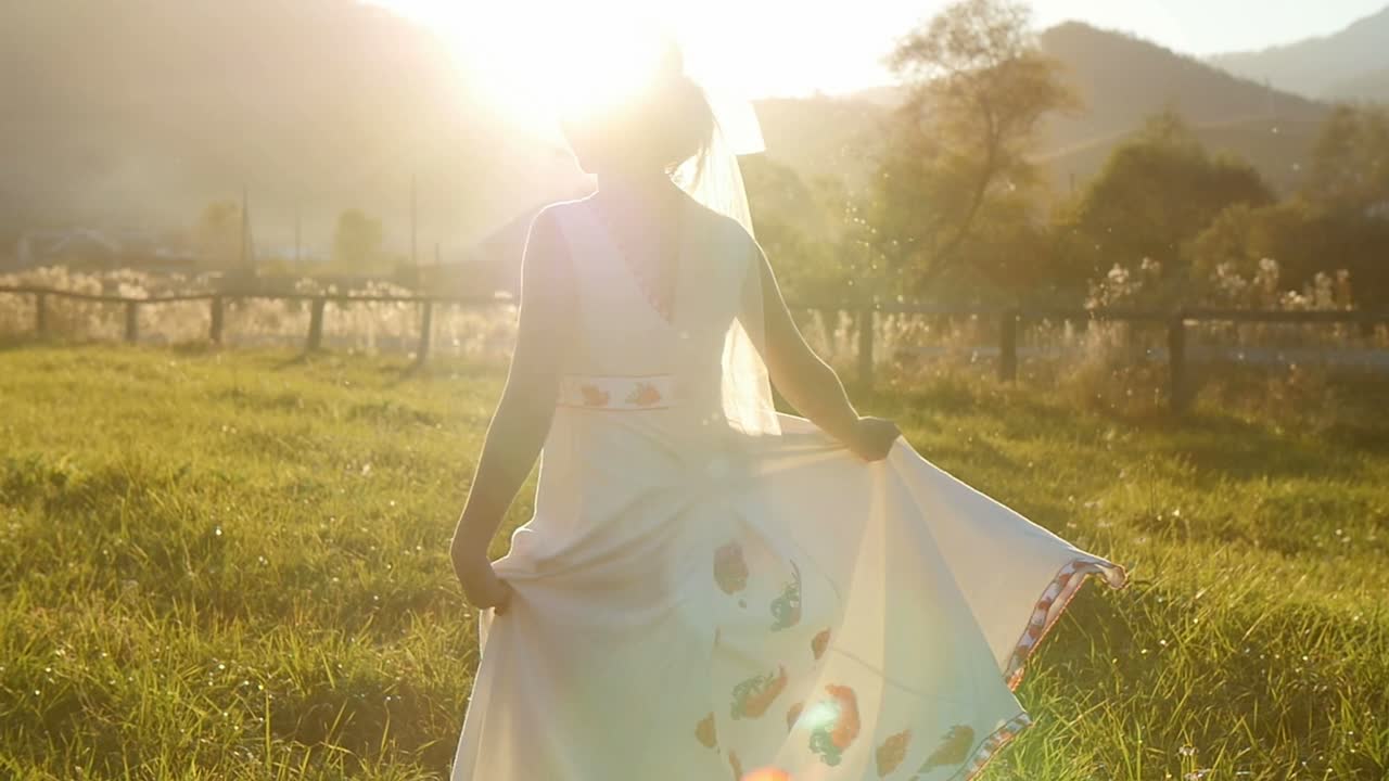 Bride walking in a field at sunset