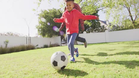 Happy-african-american-father-and-his-son-playing-football-in-garden