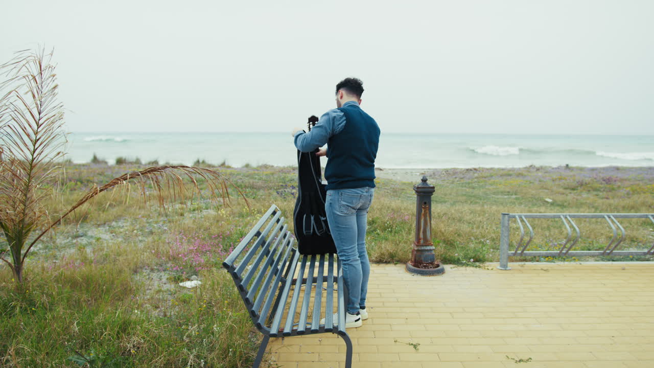 Man with Guitar Case on a Beach Bench