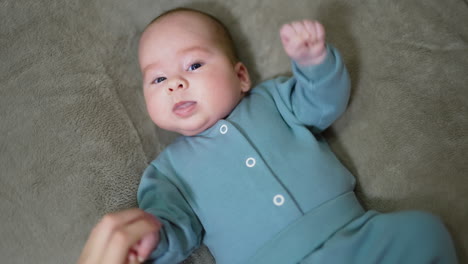 baby lying down in a green jumpsuit
