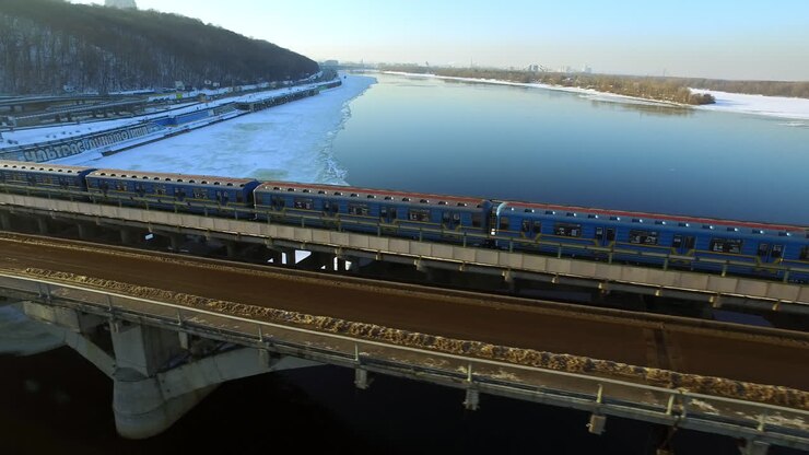Aerial view of subway train driving on bridge on winter city