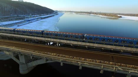 воздушный вид поезда метро, движущегося по мосту на зимнем городе