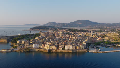 Establishing drone shot of Old Corfu town on Ionian sea during sunrise with swallows flying around