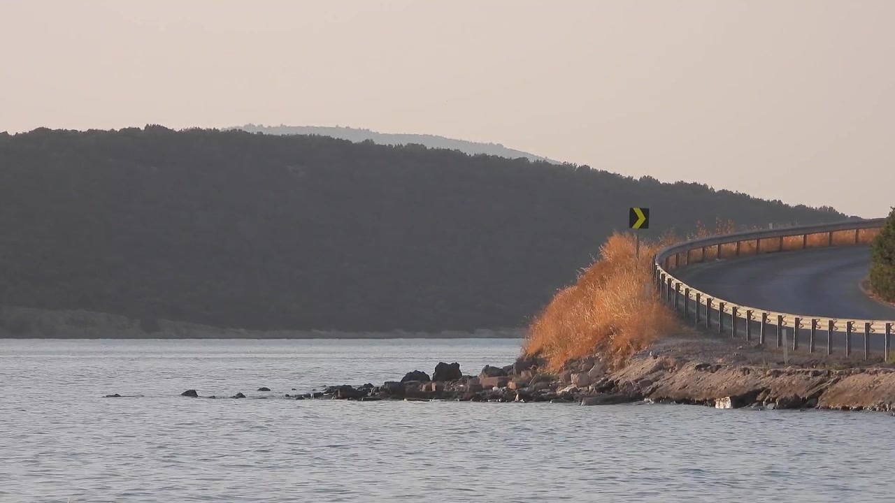 Strada costiera che si snoda lungo il mare al tramonto