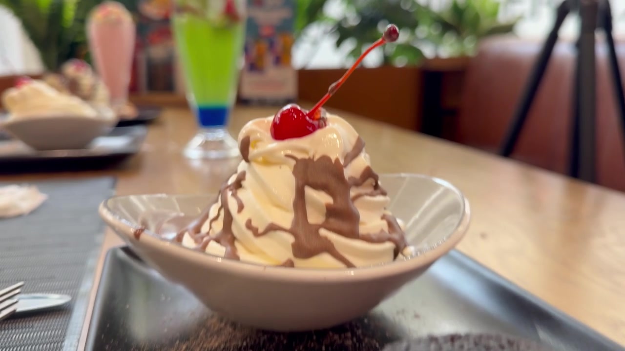Tortino al cioccolato con cuore morbido, coppa di gelato alla vaniglia e guarnizione di ciliegie, in un ambiente da caffè.