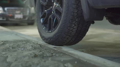 a car or truck is parked with its back wheel on a sidewalk curb on a wintery evening