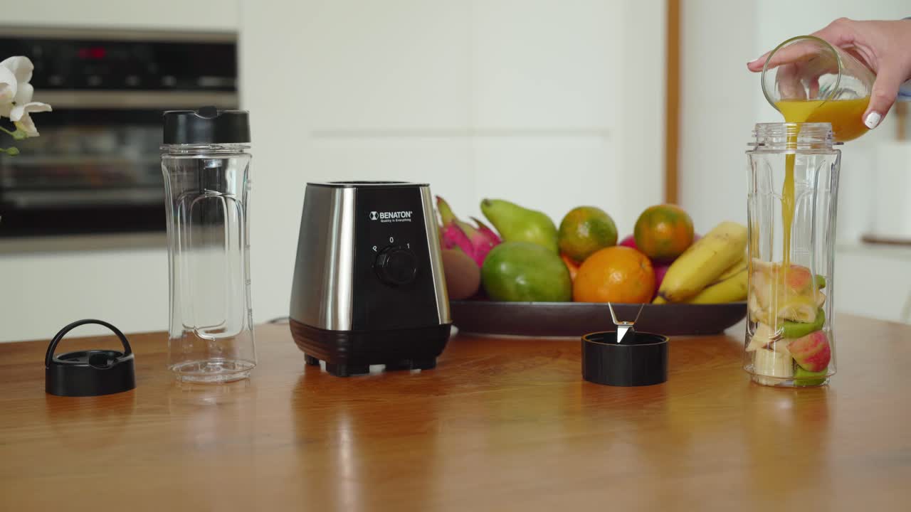 Mano che versa il succo nel bicchiere del frullatore, preparando per fare un frullato