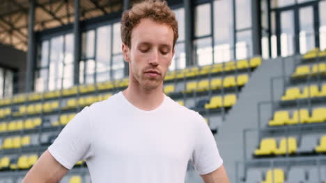 atleta masculino de fitness calentando y estirando el cuello en el estadio