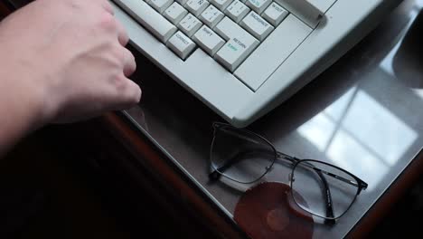 Person-Typing-on-a-Typewriter-With-Their-Glasses-on-the-Desk-in-Slow-Motion