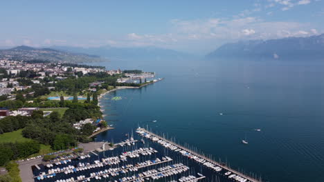 slow rising aerial view above sailboats in a harbor along lake geneva in lausanne, switzerland