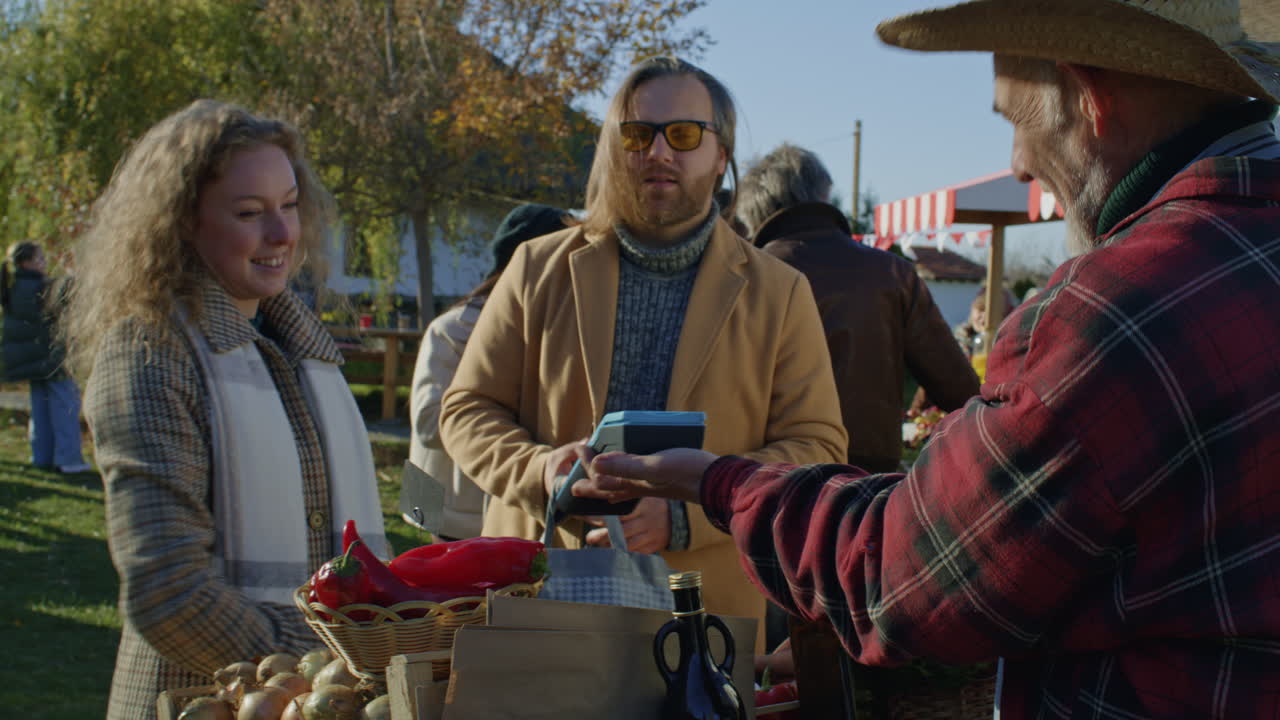 Farmer Gives Family Bag with Fruits Farmer Gives to Family Bag with Fruits or Vegetables Wife Pays for Purchase by Contactless Way Owner of Sales Point Thanks Shoppers for the Buy