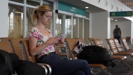 young woman using her smartphone, relaxing at the airport