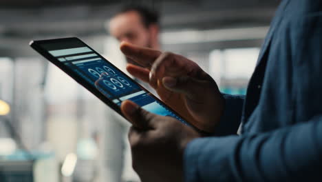 vertical video close up of black employee engages in charts analysis session on tablet
