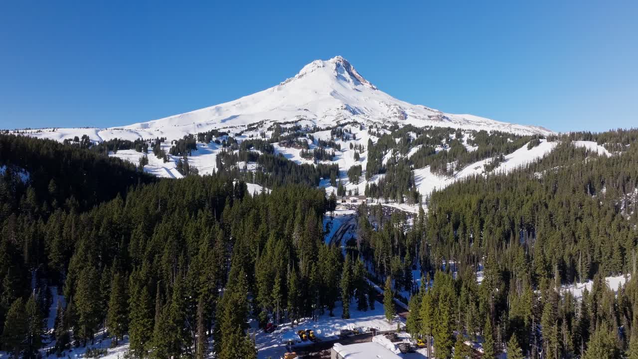 Vista aerea con drone in lenta ascesa del Monte Hood, dei suoi ghiacciai e della fitta coltre di neve sulla cima del vulcano solitario di fronte al Meadows Ski Resort, nella regione nord-occidentale del Pacifico, vicino a Hood River e Portland (Oregon).