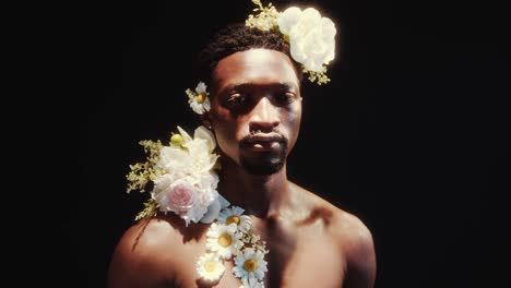 portrait of shirtless african american man adorned with flowers