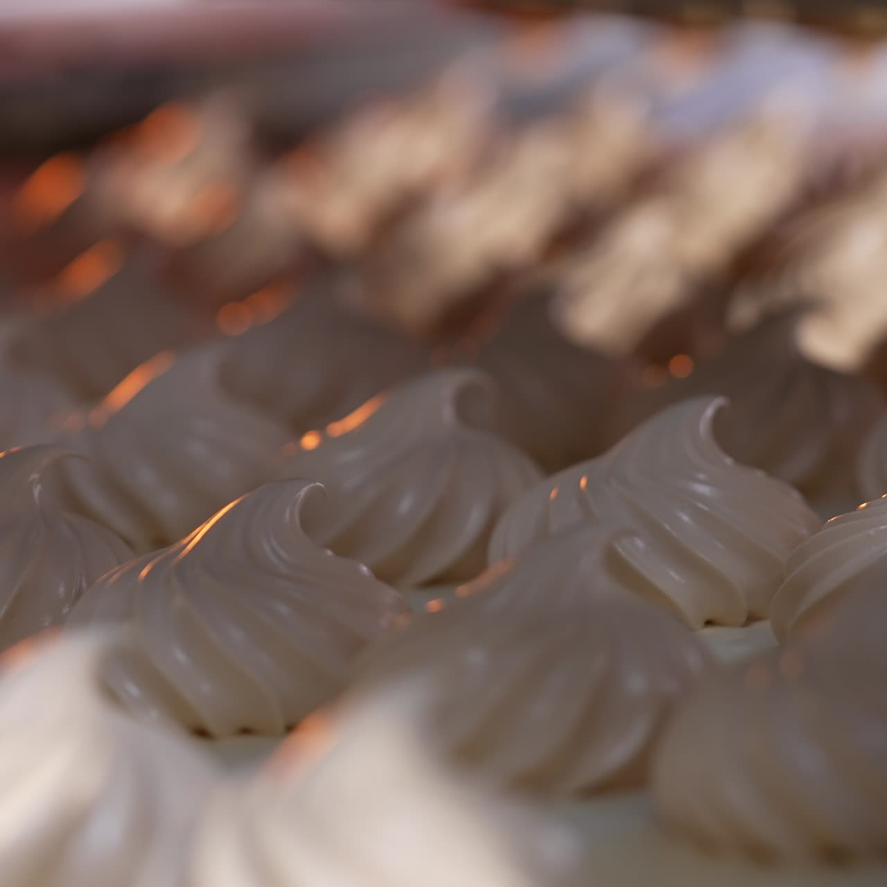 White creamy marshmallows identical in size and shape. Vanilla zephyr manufactured at food factory. Close up