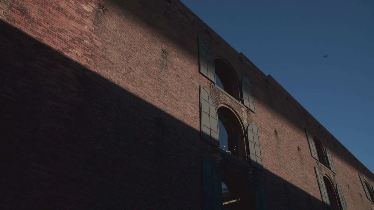 Shadows and a beam of light cast on a brick wall in Brooklyn