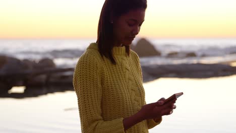 Woman-using-mobile-phone-on-the-beach-4k