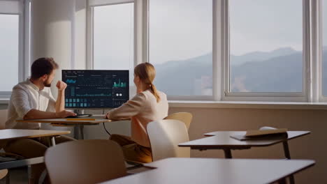 two people analyzing data on a computer in a modern office setting