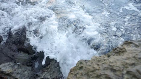 Waves-crashing-into-rocks-near-Budva-old-town-on-the-coastline-of-Montenegro-on-the-Adriatic-coastline-on-a-sunny-sunset-afternoon