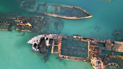 drone de arriba hacia abajo primer plano barcos oxidados, naufragio, agua azul océano vista aérea del mar, historia marina con viejos vehículos oxidados