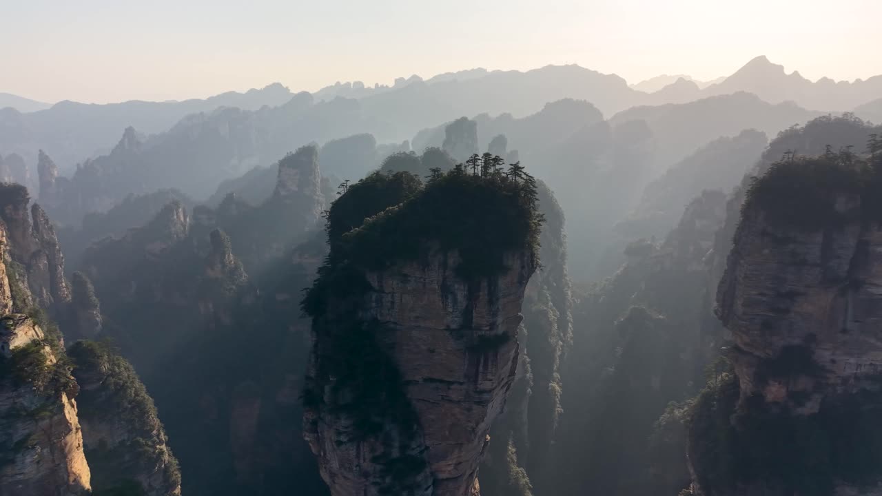 Drone aerial of Zhangjiajie Avatar mountains bathed in golden sunrise light with mist layers, dreamy China scenery