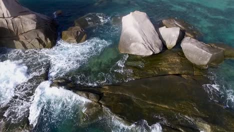 waves hitting rocks drone turn camera left from above middle shot