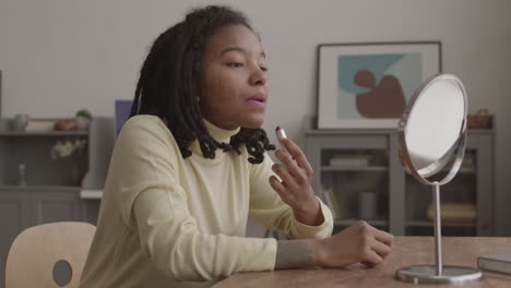 young african woman applying lipstick