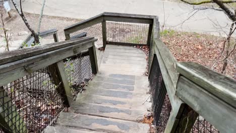 man-walking-slow-motion-down-a-wooden-staircase-in-a-usa-park-cove-spring-frankfort-kentucky-4k