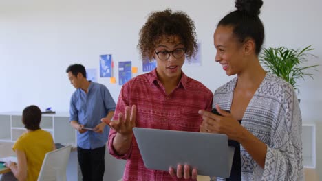 felices colegas de negocios de raza mixta discutiendo sobre una computadora portátil en una oficina moderna 4k