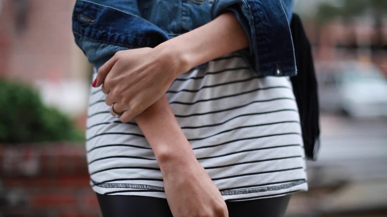 Young woman in fashionable clothes standing and waiting in the street